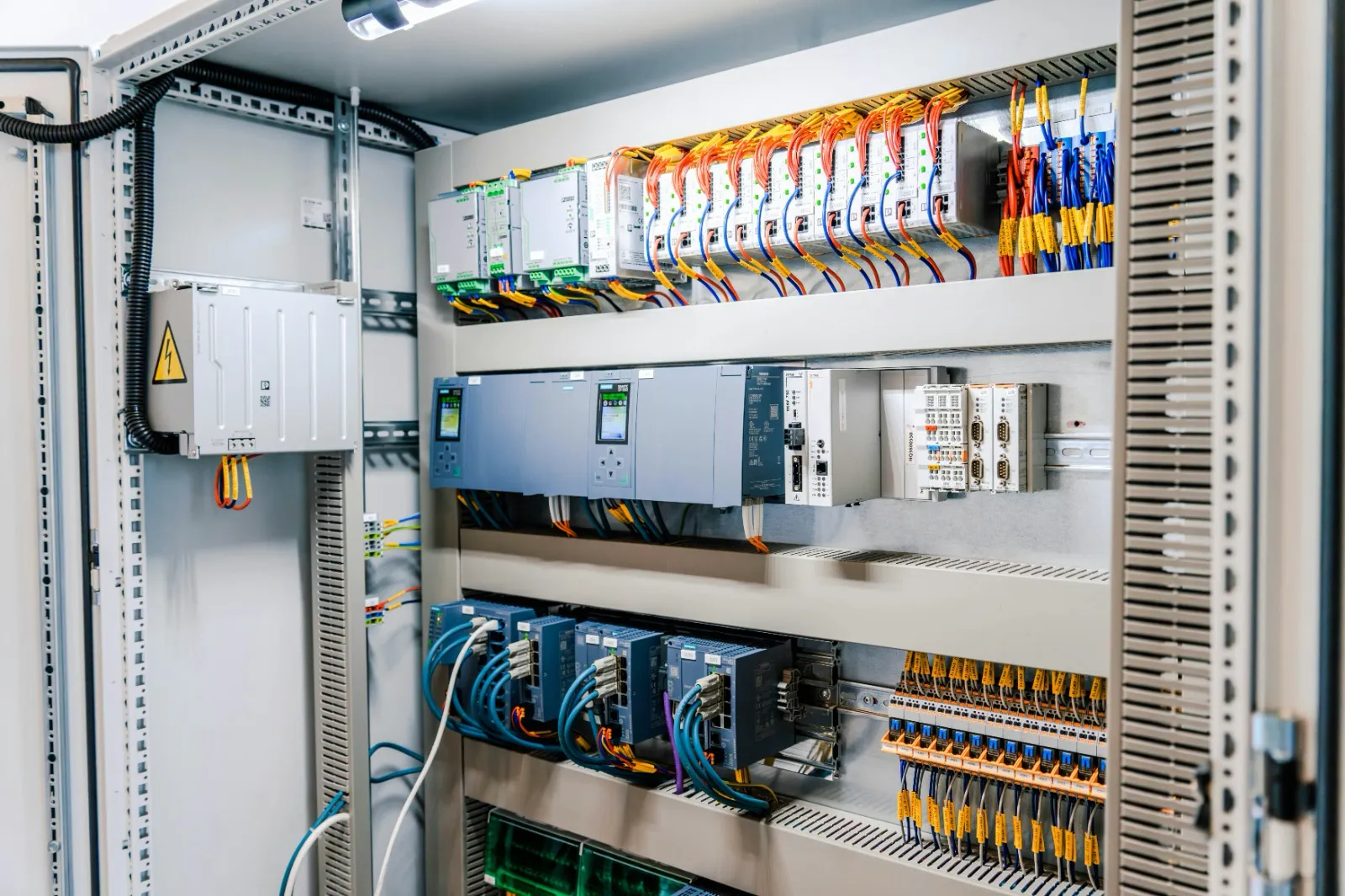 Geöffneter elektrischer Schaltschrank mit Verdrahtung und Modulen – das technische Arbeitsumfeld bei Volt.